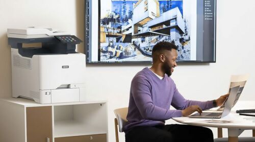 Hommes travaillant sur un ordinateur portable devant une Imprimante couleur multifonctions Xerox® VersaLink® C415